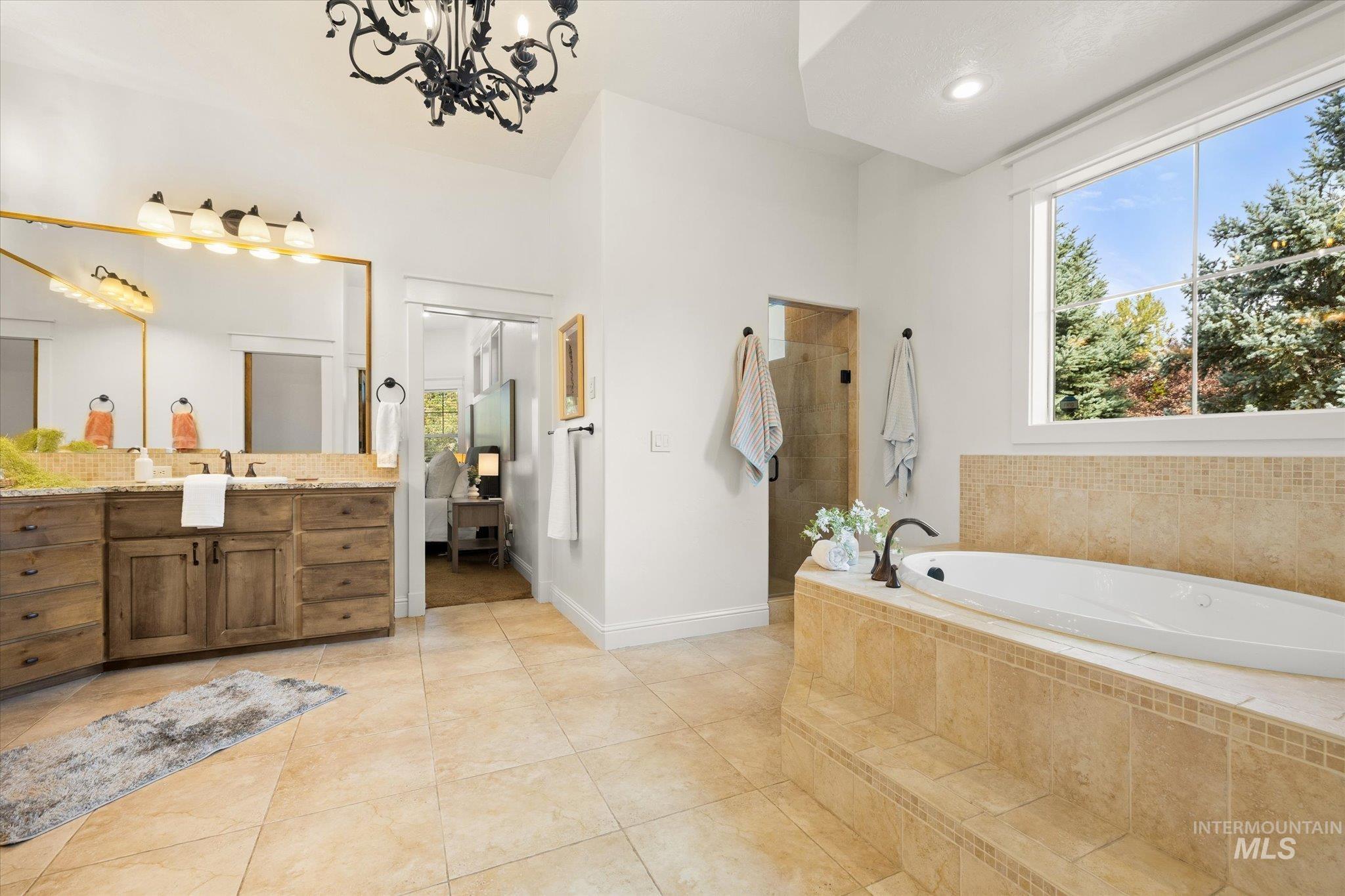 Full bath featuring a garden tub, vanity, light tile patterned floors, a chandelier, and recessed lighting