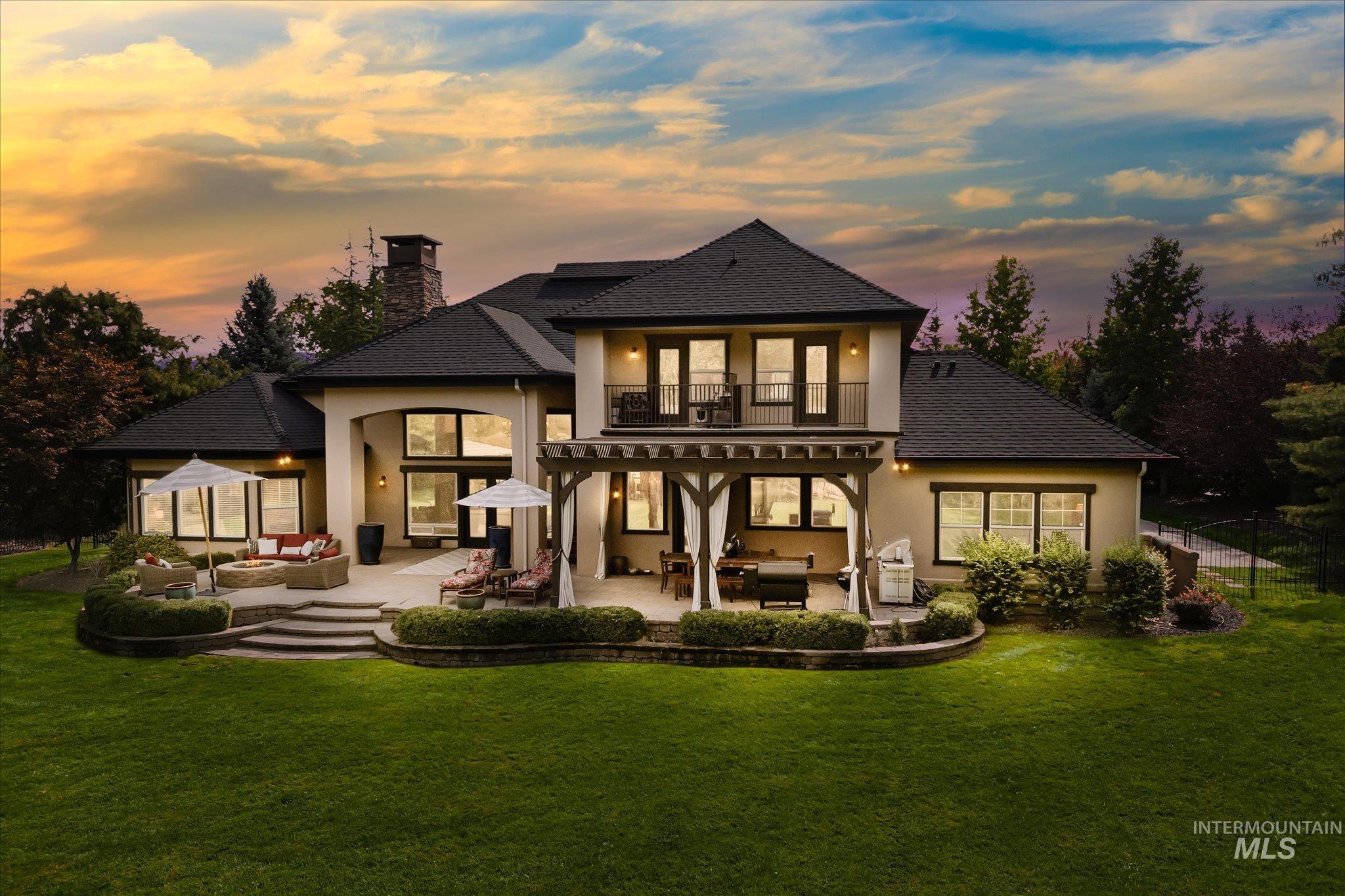Back of property at dusk with outdoor lounge area, stucco siding, a shingled roof, and a balcony