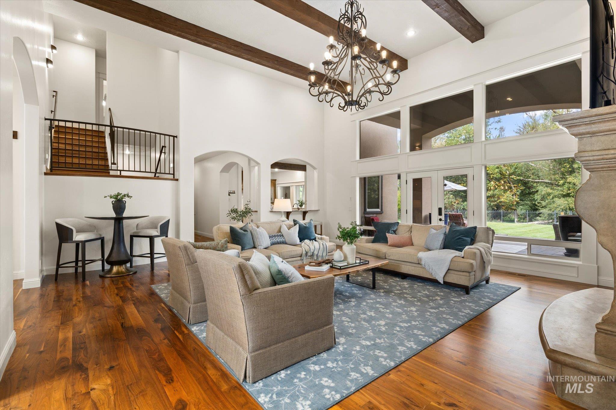 Living area featuring beam ceiling, dark wood-style flooring, a towering ceiling, recessed lighting, and a chandelier