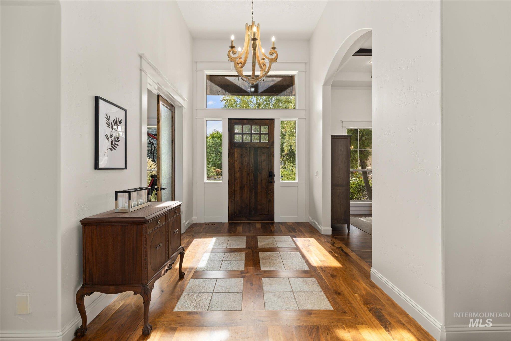 Entrance foyer featuring wood-type flooring, a chandelier, arched walkways, and inlaid floor details
