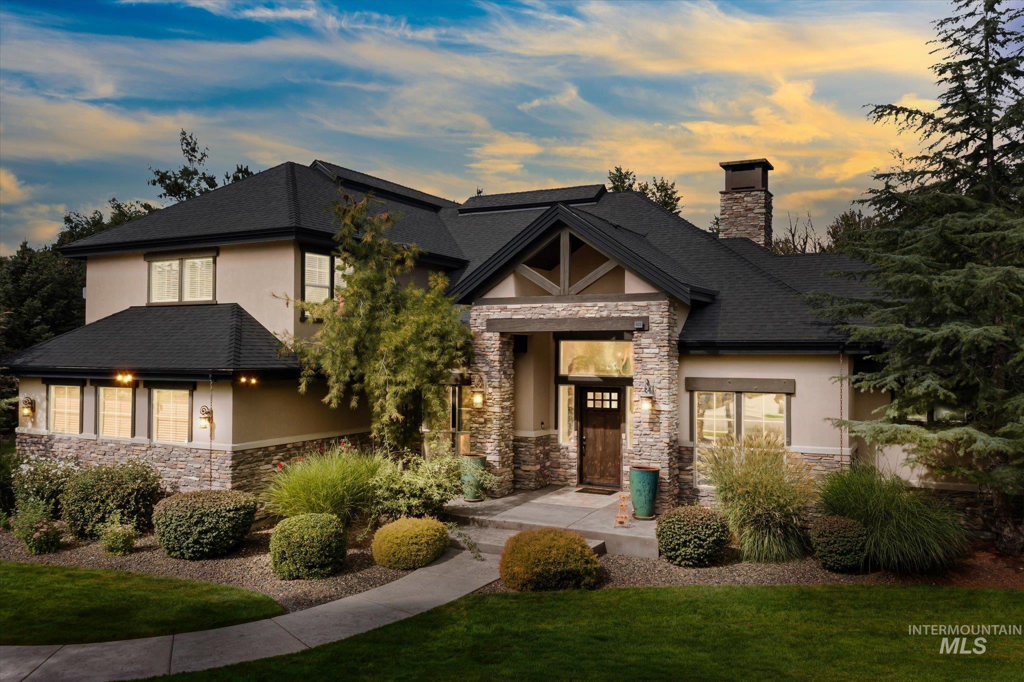 Craftsman house featuring stone siding, stucco siding, a chimney, and a front lawn