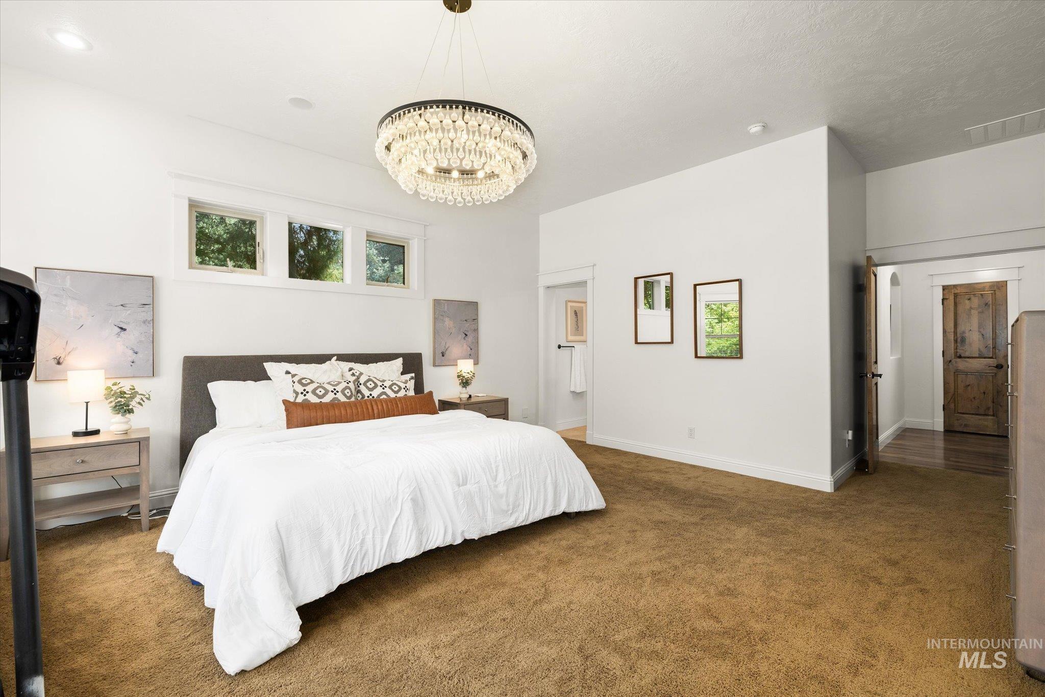Carpeted bedroom featuring baseboards and a chandelier