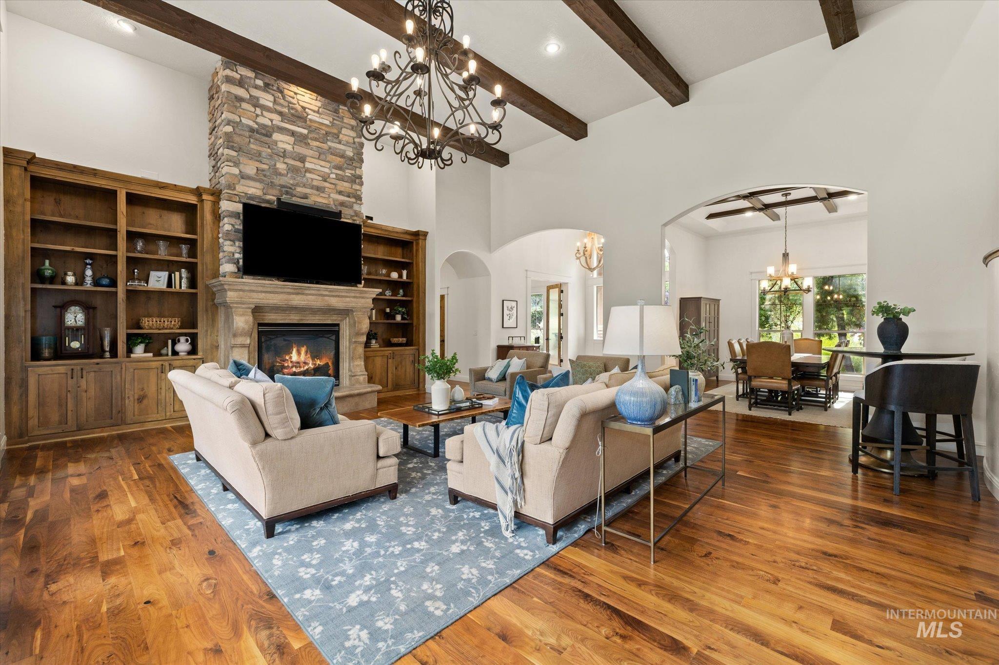 Living area with beamed ceiling, arched walkways, a chandelier, a fireplace, and a high ceiling
