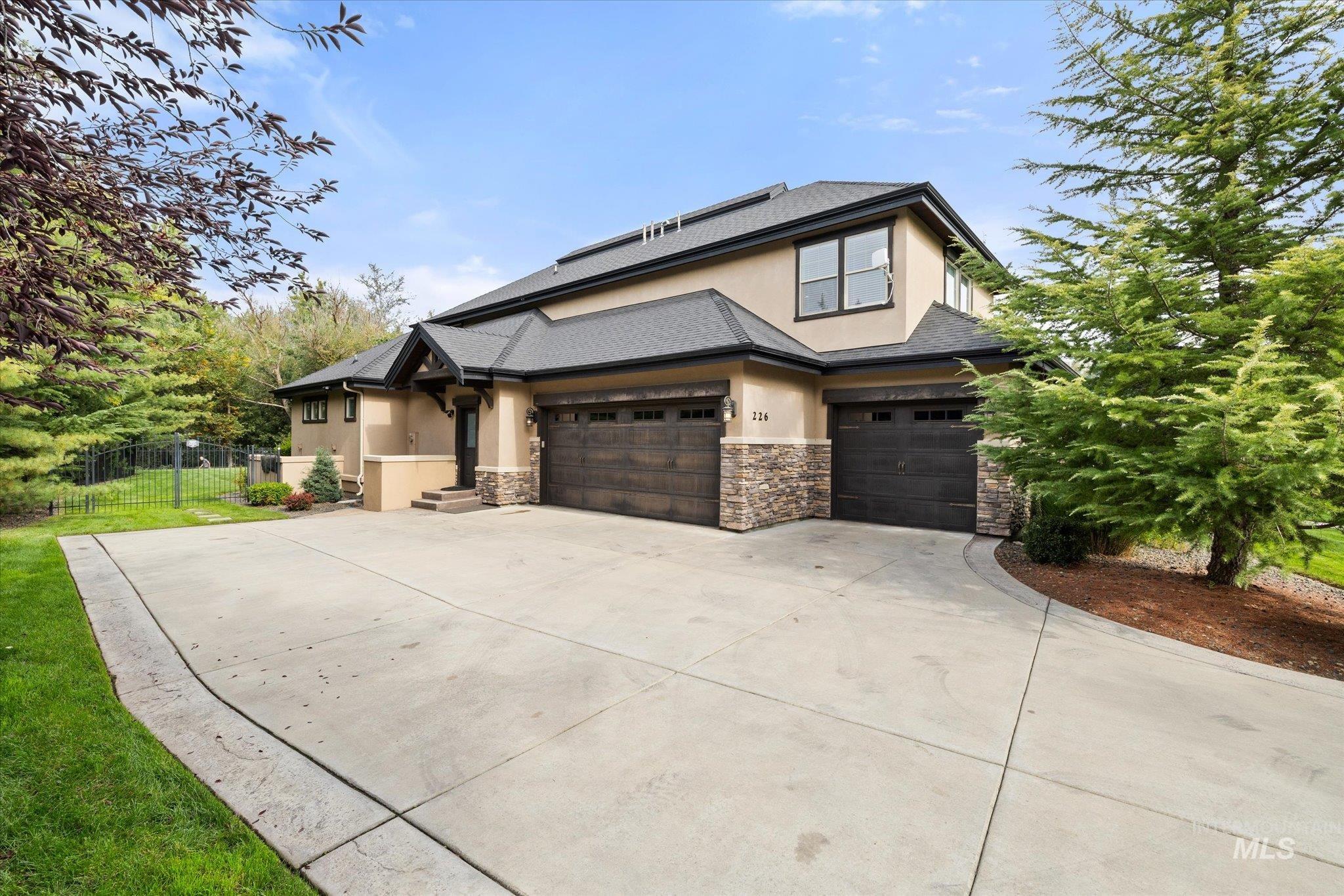 View of front of house with solar panels, stucco siding, stone siding, and concrete driveway