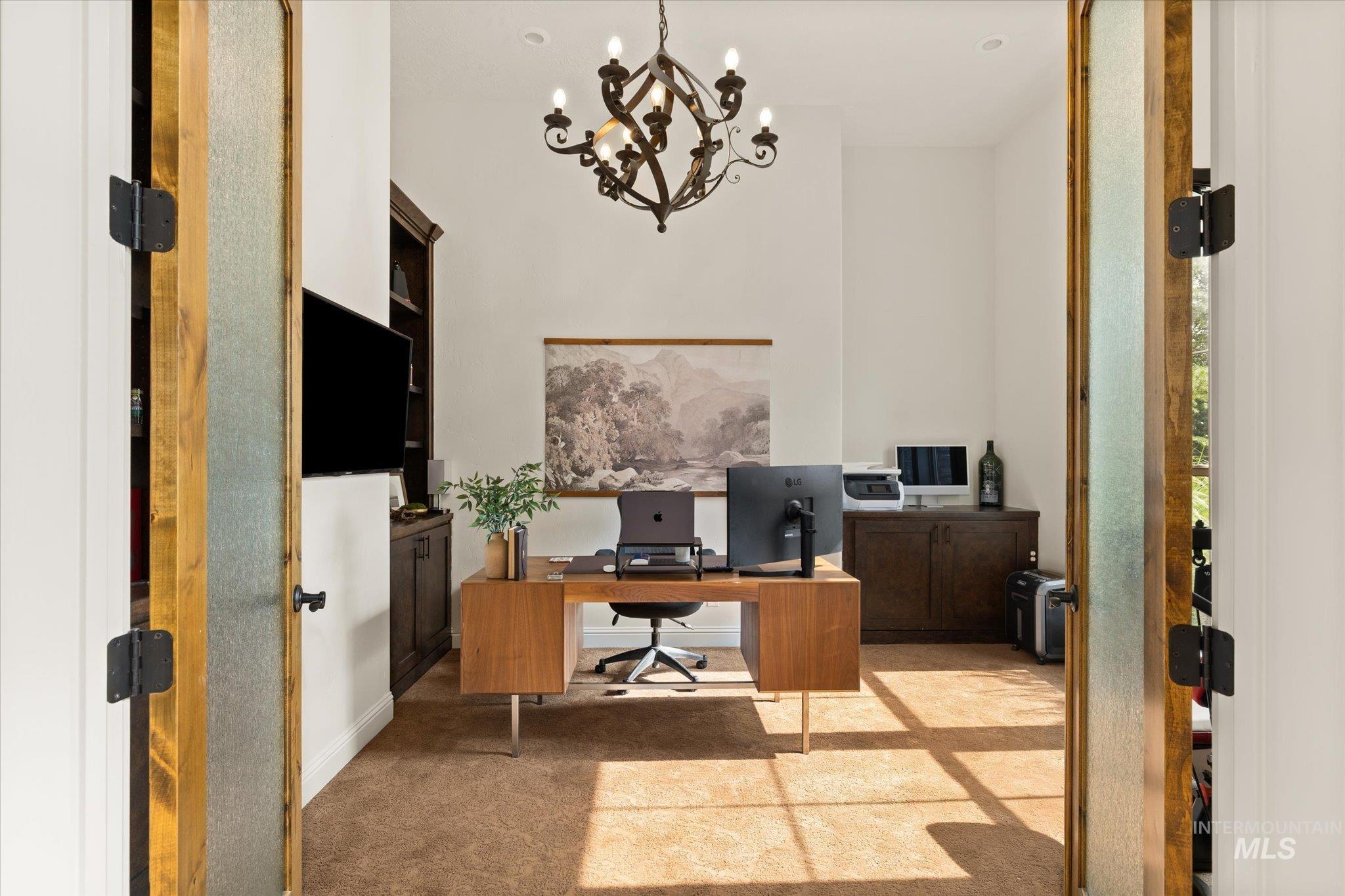 Home office featuring light carpet and a chandelier