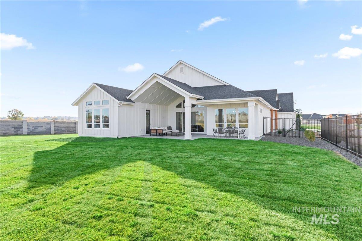 Back of property with a fenced backyard, a patio area, board and batten siding, and a shingled roof