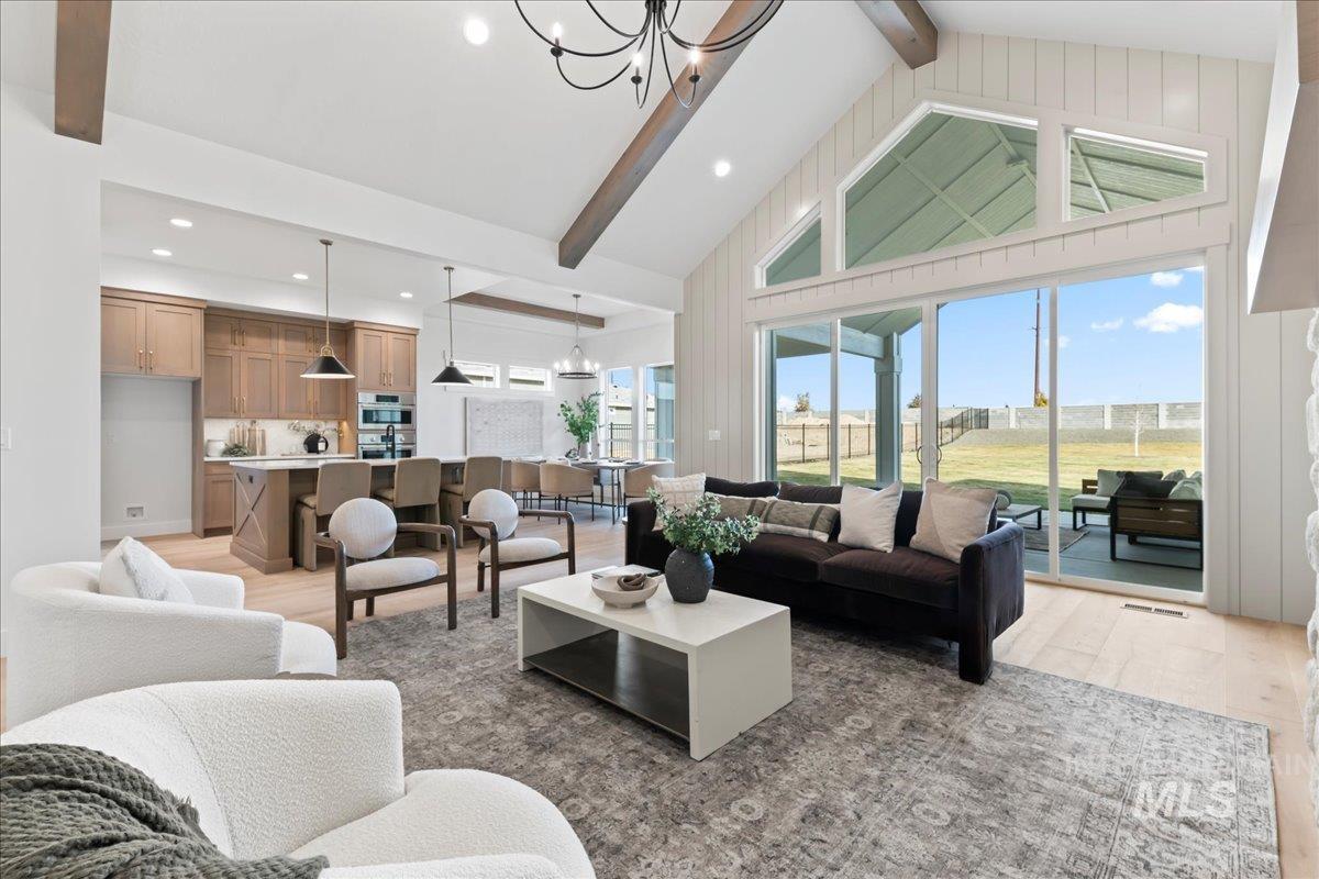 Living area featuring a chandelier, beam ceiling, light wood-style flooring, high vaulted ceiling, and recessed lighting