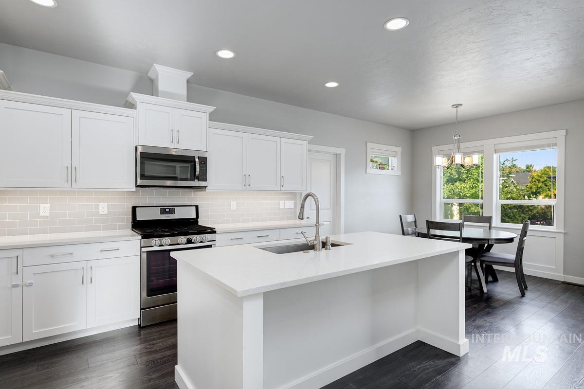 Kitchen with stainless steel appliances, recessed lighting, backsplash, a center island with sink, and light countertops