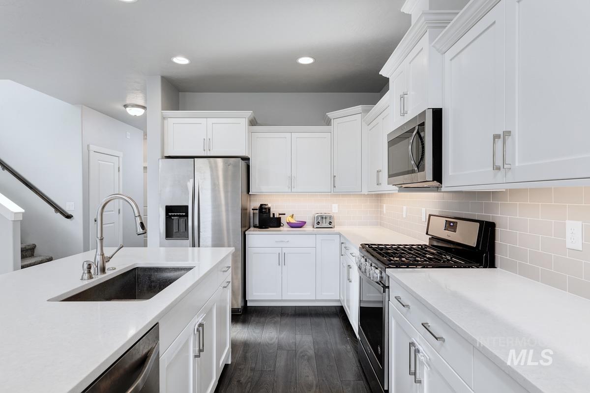 Kitchen featuring appliances with stainless steel finishes, tasteful backsplash, white cabinets, light countertops, and recessed lighting