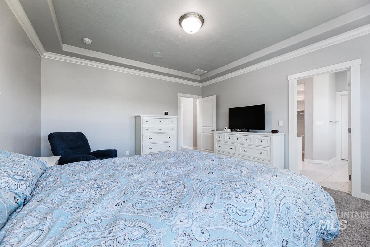 Tiled bedroom featuring crown molding, carpet flooring, and a tray ceiling