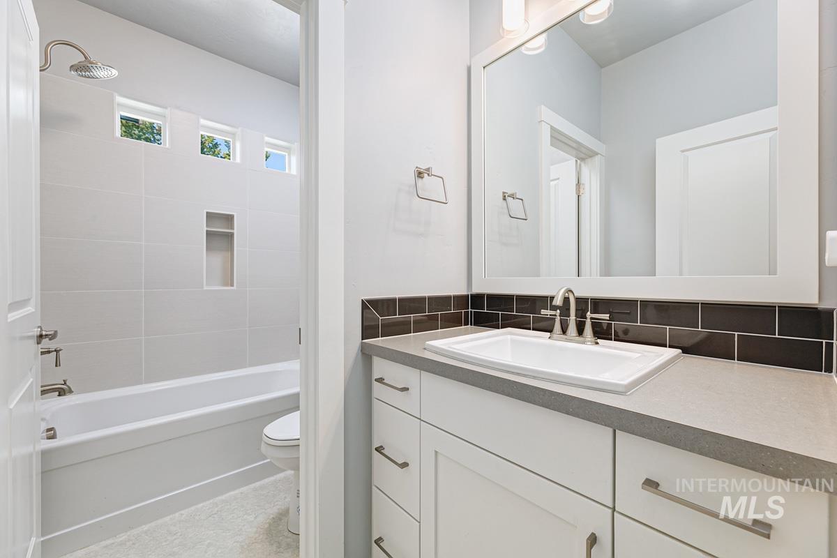 Full bath with vanity, shower / bathtub combination, and tasteful backsplash