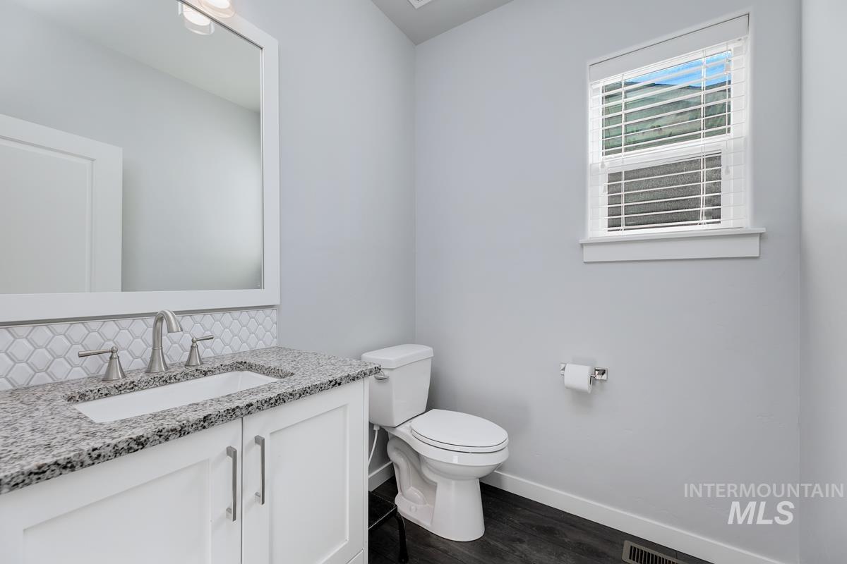Bathroom with tasteful backsplash, vanity, and wood finished floors