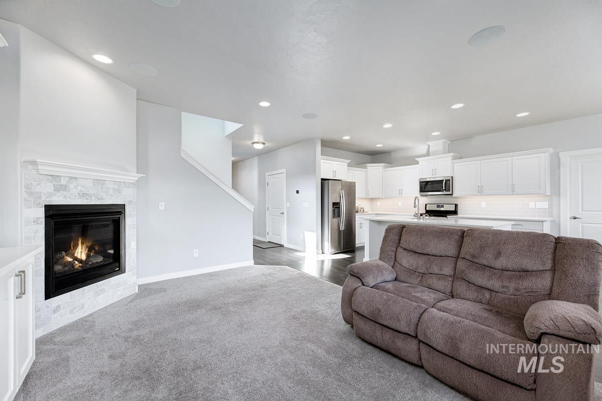 Living room with recessed lighting, dark colored carpet, and a glass covered fireplace
