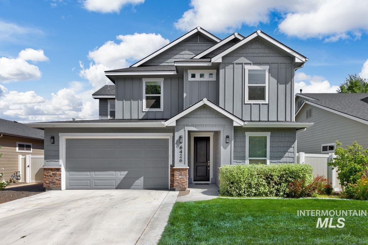 Craftsman-style house with concrete driveway, board and batten siding, stone siding, and an attached garage