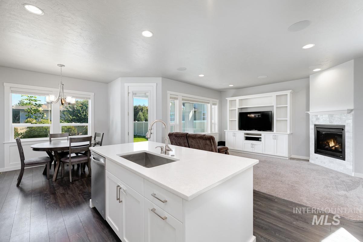 Kitchen featuring recessed lighting, plenty of natural light, a tiled fireplace, a chandelier, and dark wood-style flooring