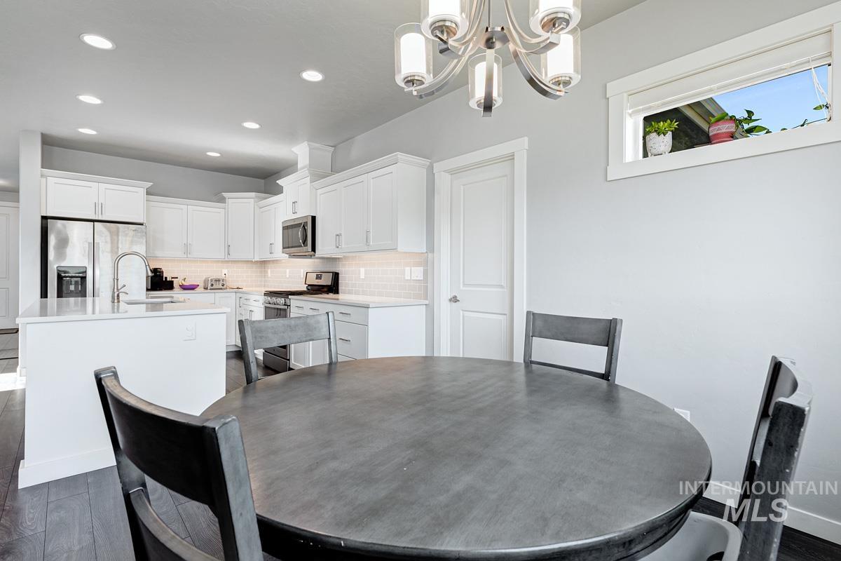 Dining area featuring dark wood-style flooring, a chandelier, and recessed lighting