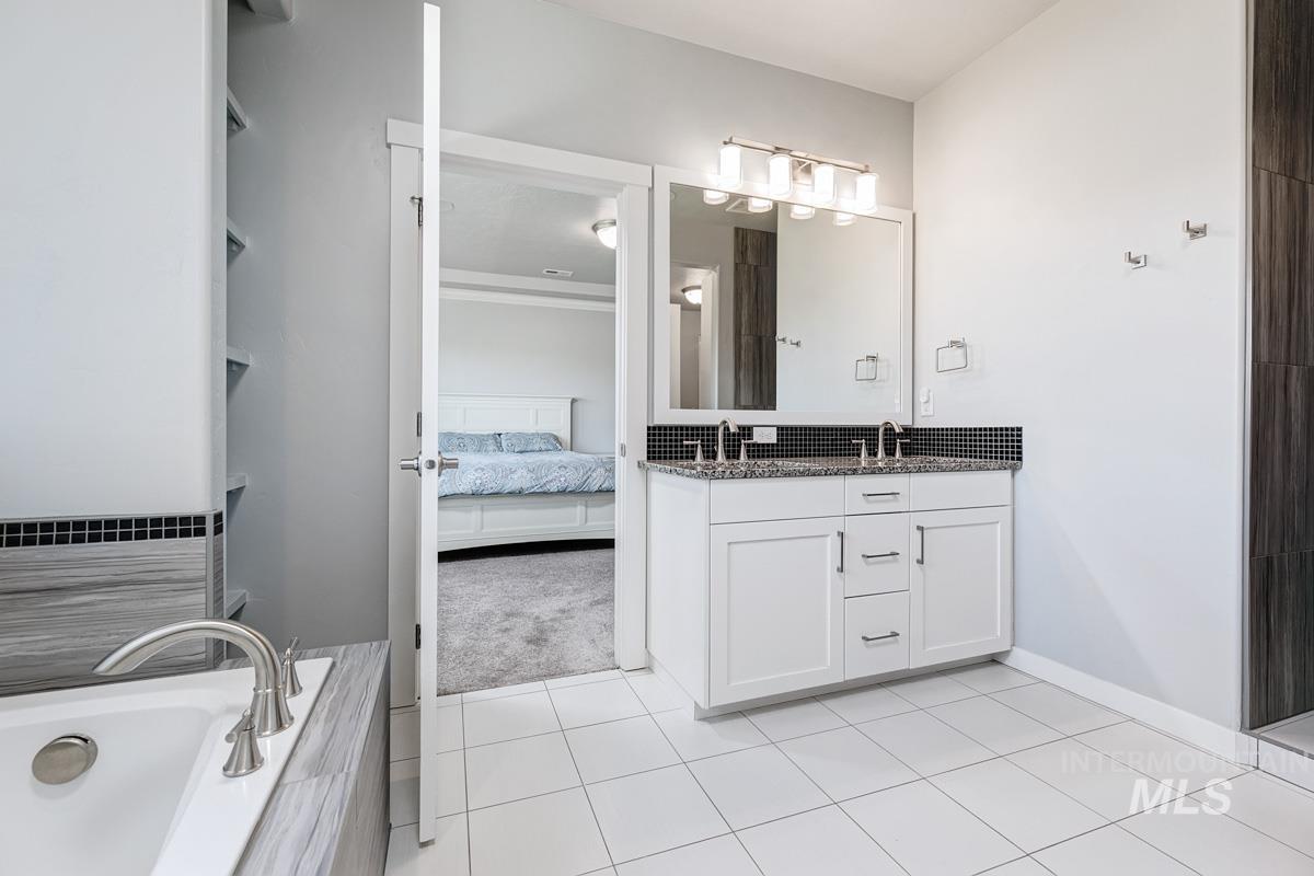Full bathroom with double vanity, a bath, tile patterned flooring, and ensuite bath