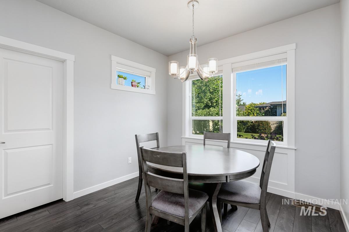 Dining area with a chandelier and dark wood-type flooring