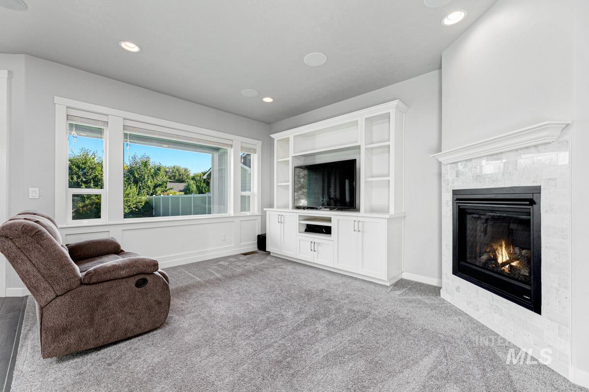 Carpeted living area with a tile fireplace and recessed lighting