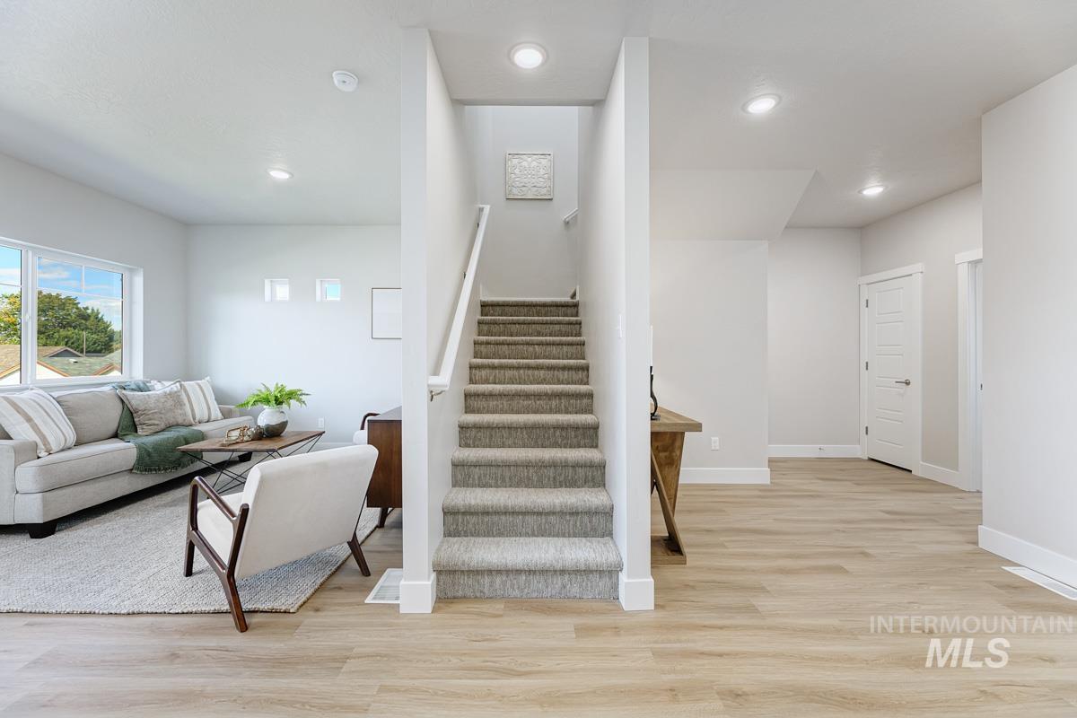 Staircase with wood finished floors and recessed lighting