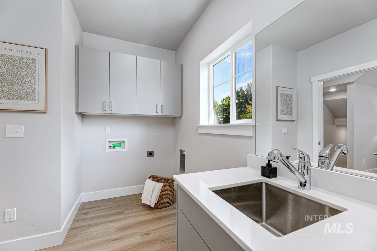 Washroom featuring washer hookup, light wood-style flooring, electric dryer hookup, and cabinet space