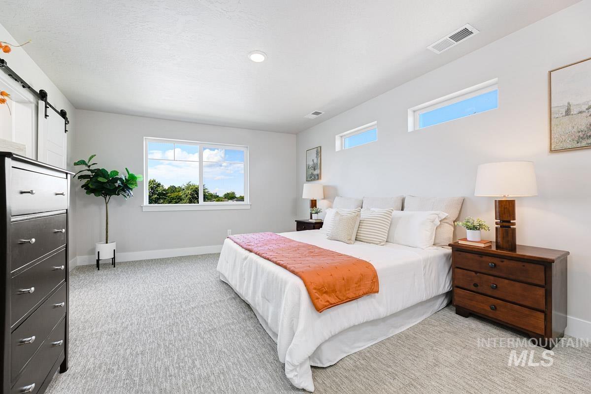 Bedroom featuring a barn door, light colored carpet, and recessed lighting
