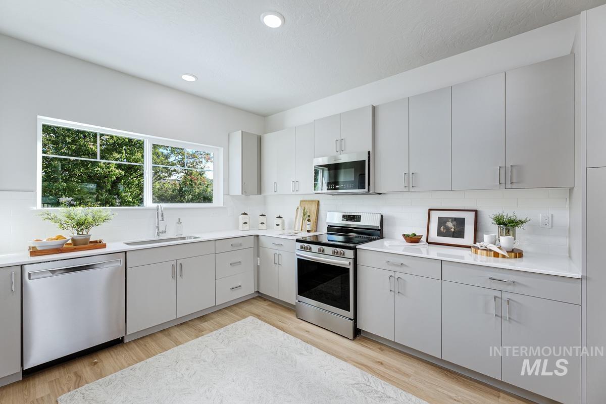 Kitchen featuring stainless steel appliances, decorative backsplash, gray cabinetry, and recessed lighting