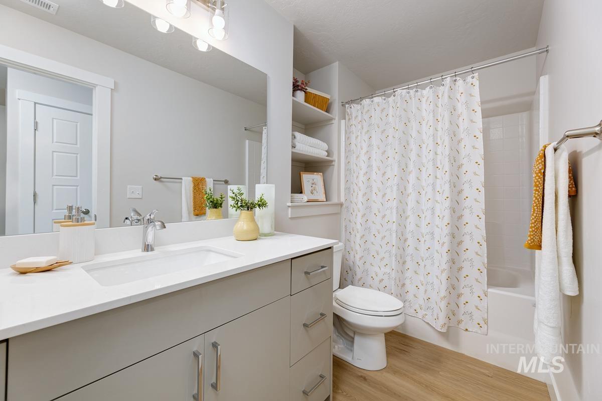 Bathroom with shower / bath combo with shower curtain, vanity, and light wood-type flooring