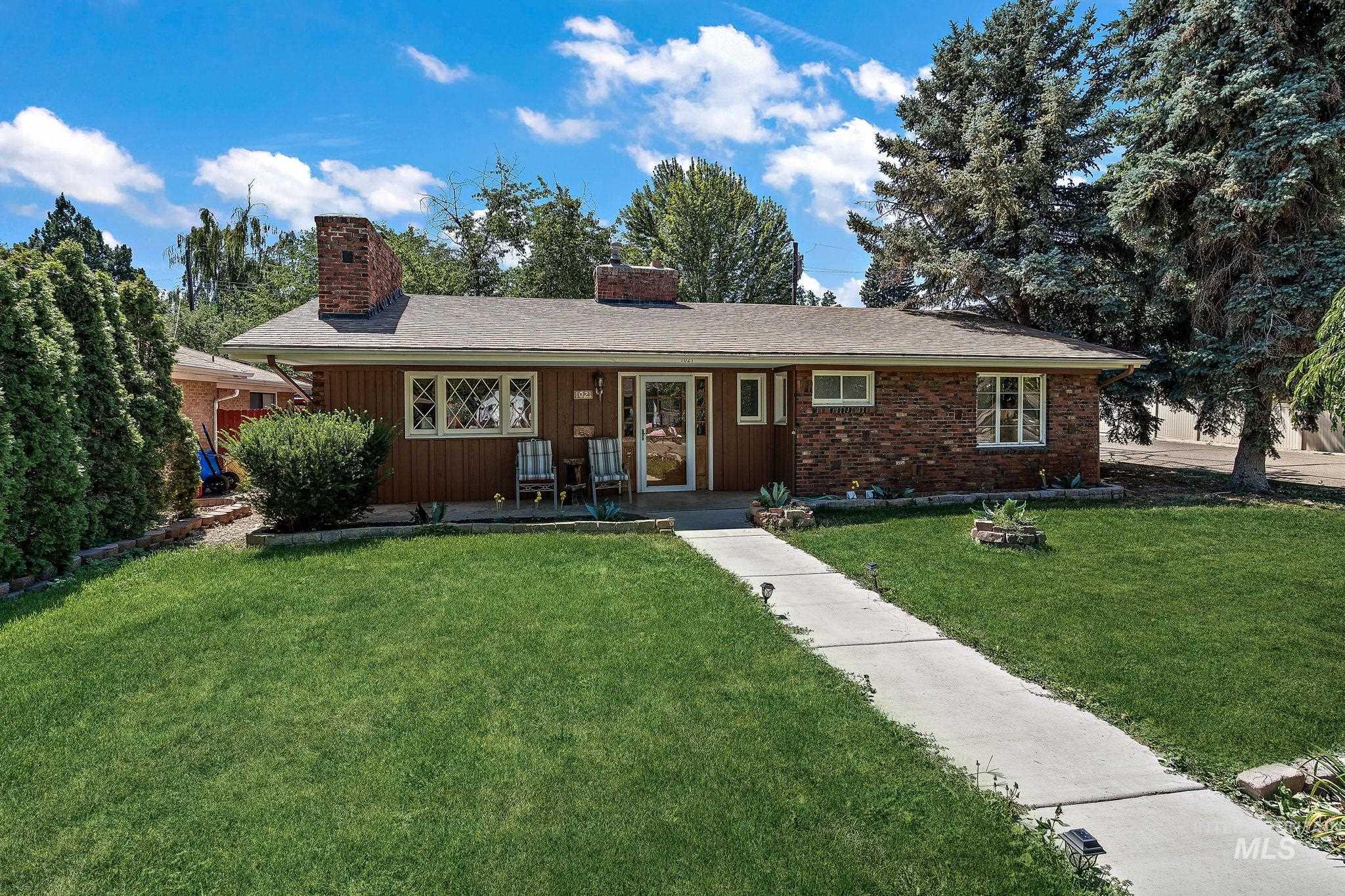 Single story home with a front yard, a chimney, brick siding, and board and batten siding