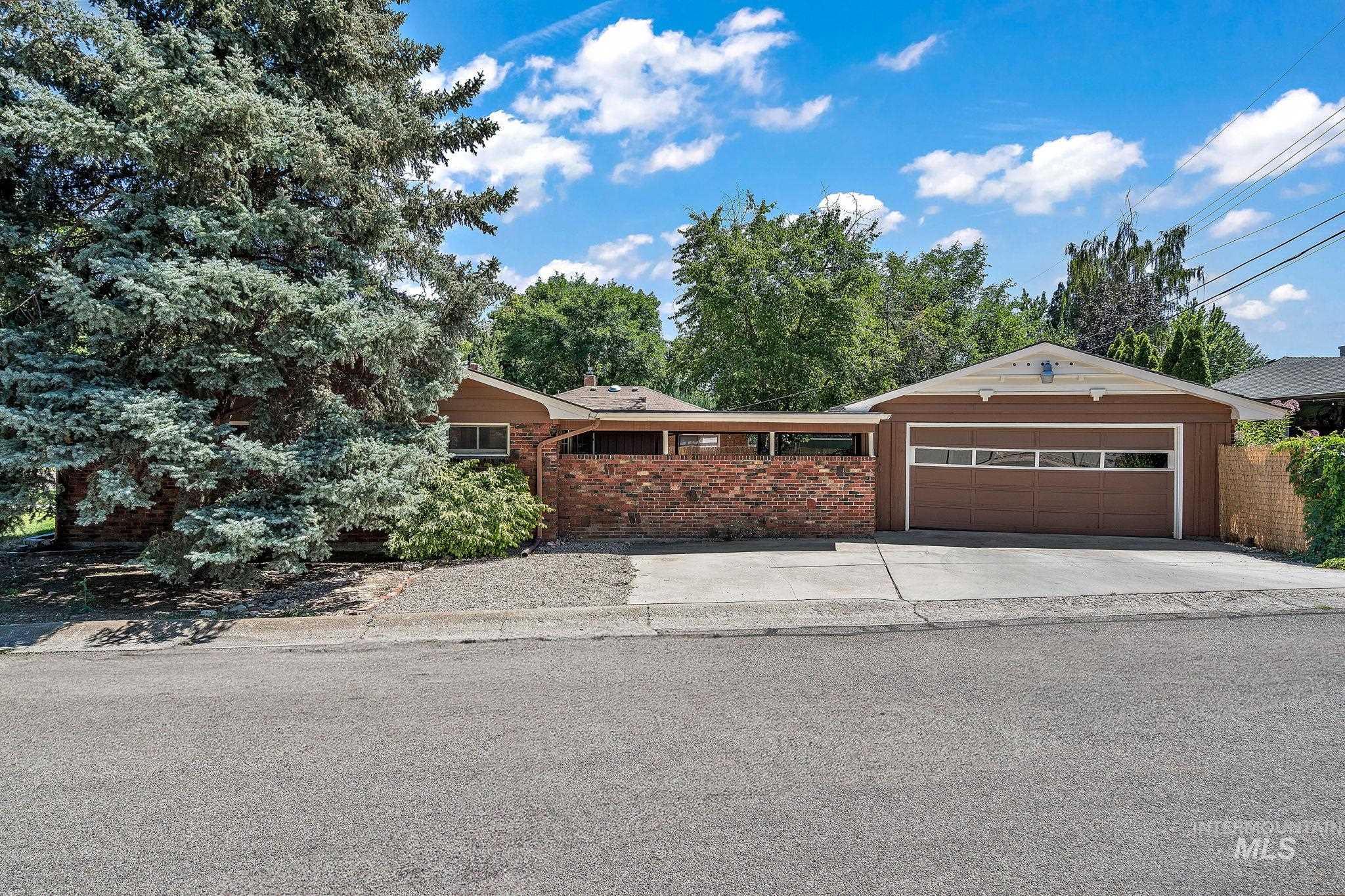 View of front facade featuring a garage, concrete driveway, and brick siding