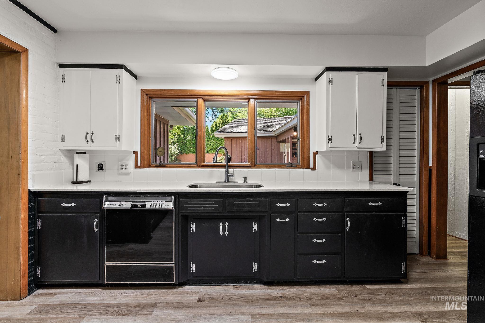 Kitchen with dark cabinets, decorative backsplash, white cabinetry, and black appliances
