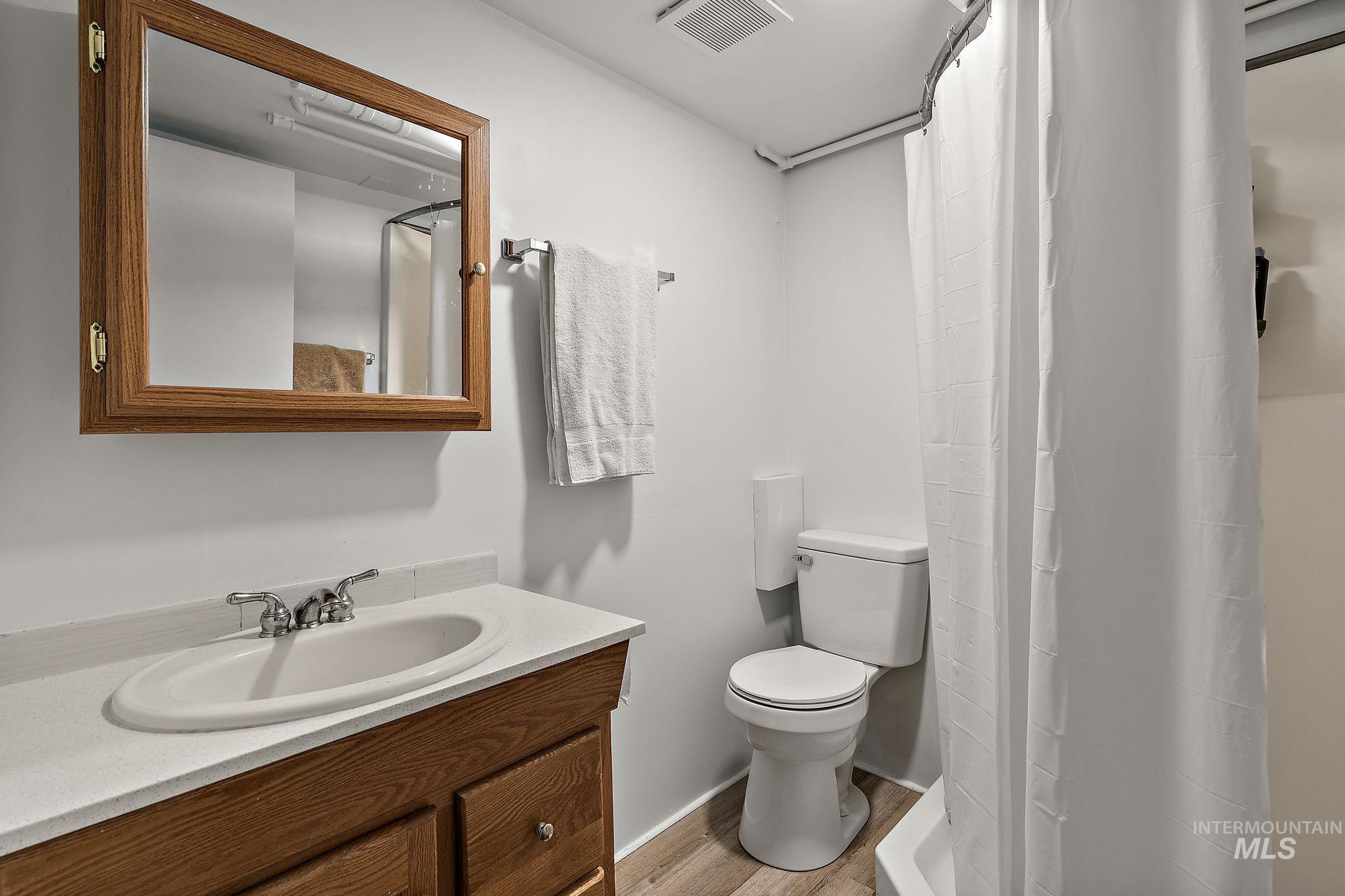 Full bath with vanity, wood finished floors, and a shower with shower curtain