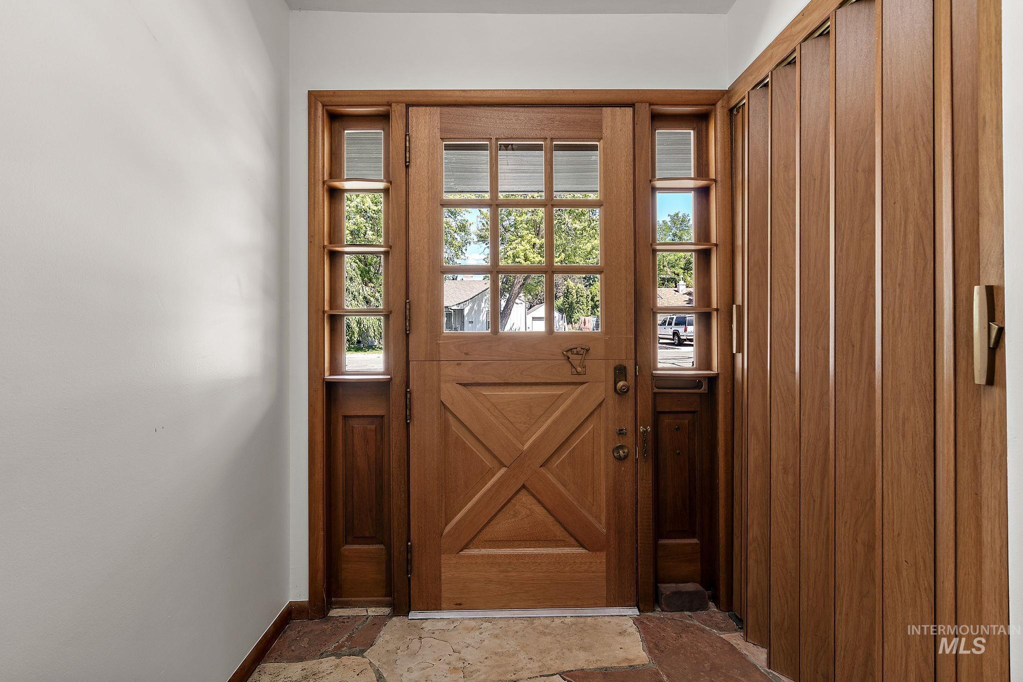 Doorway featuring stone tile floors and baseboards