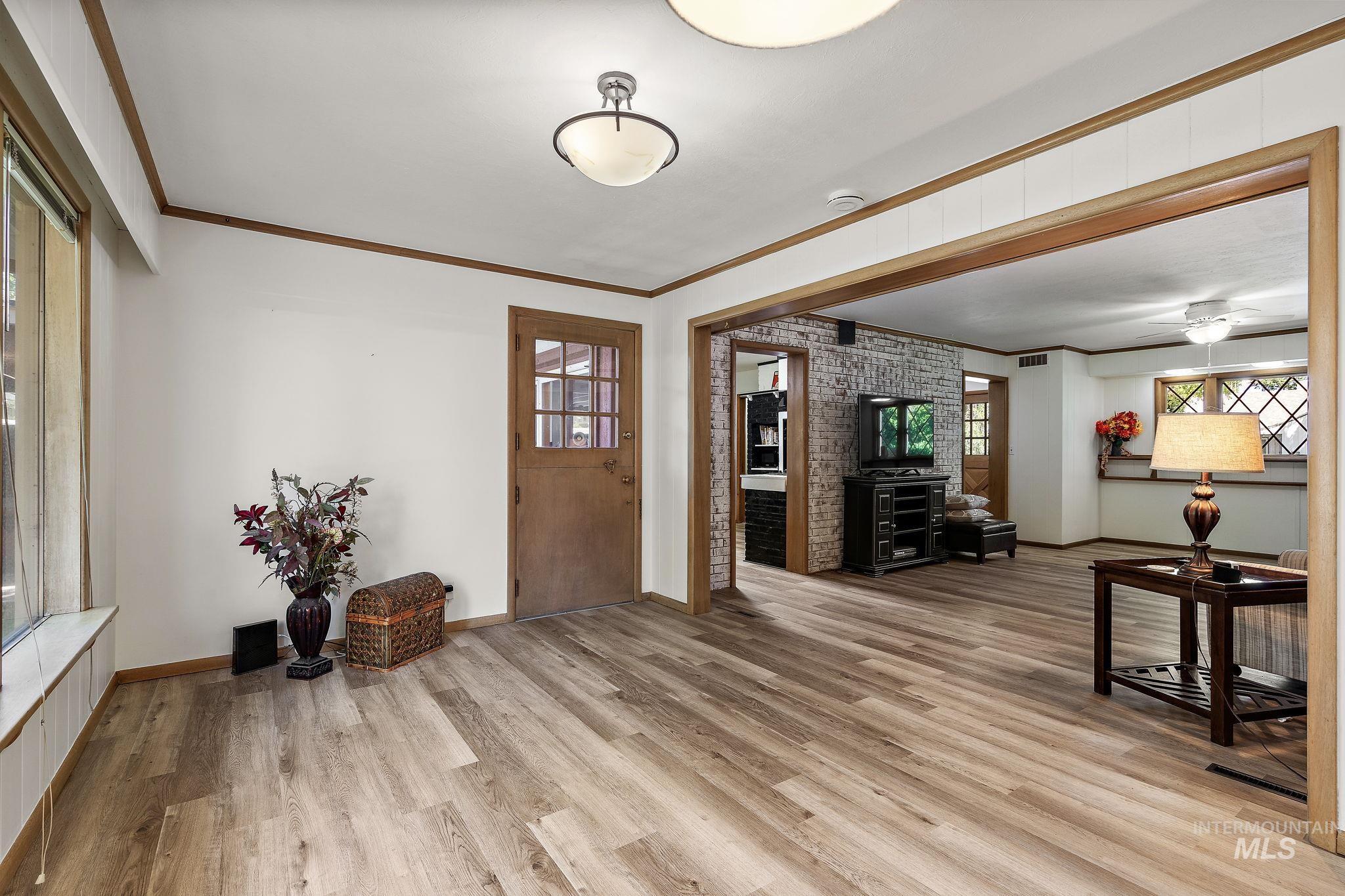 Entryway with crown molding, light wood-style floors, and ceiling fan