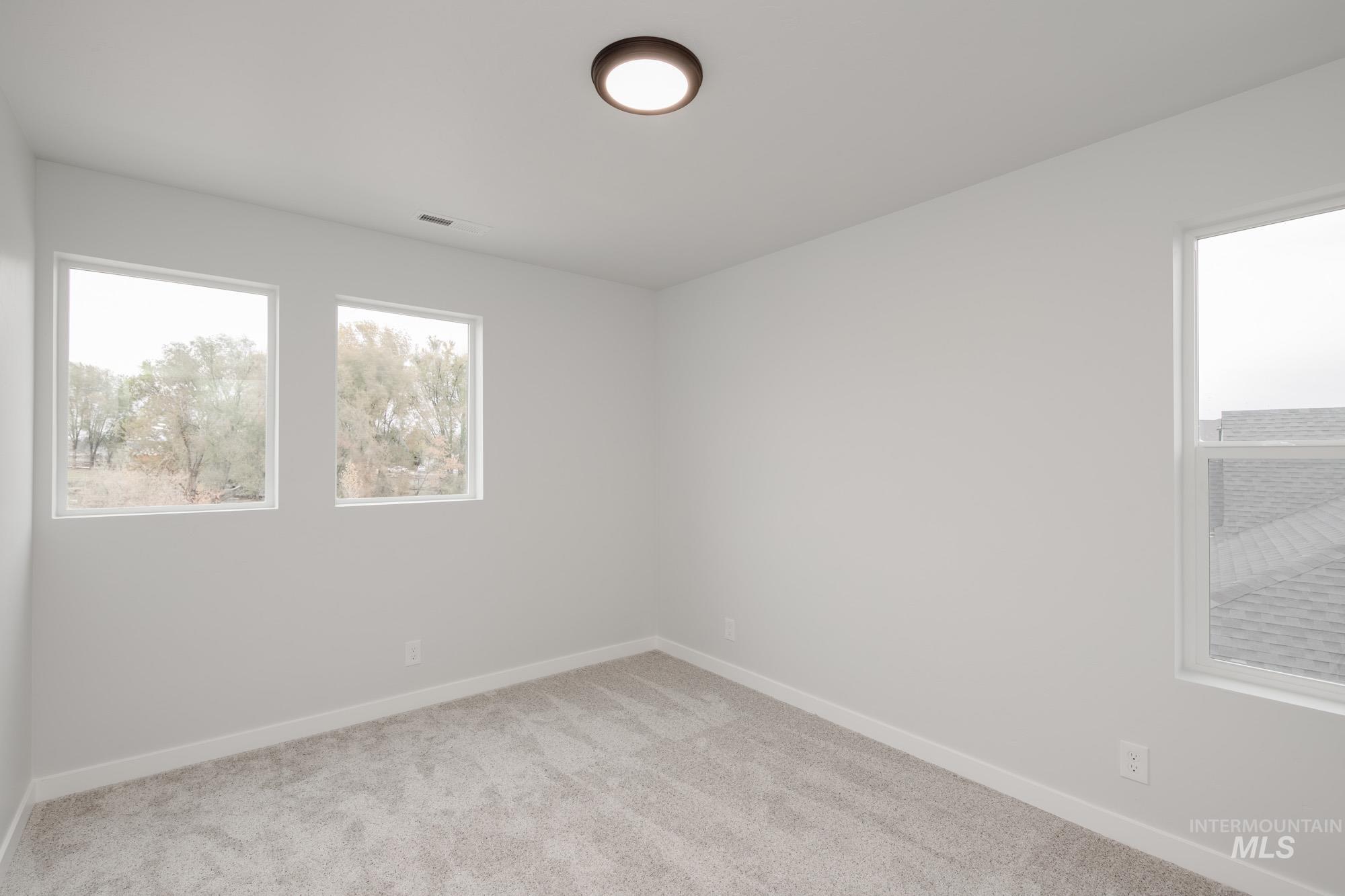 Empty room featuring light colored carpet and baseboards