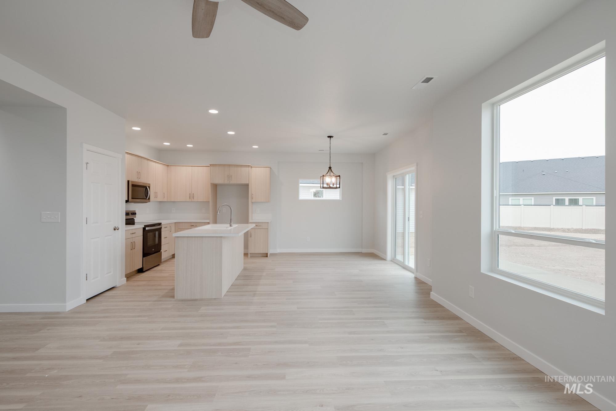 Kitchen featuring light countertops, stainless steel appliances, light wood finished floors, recessed lighting, and an island with sink