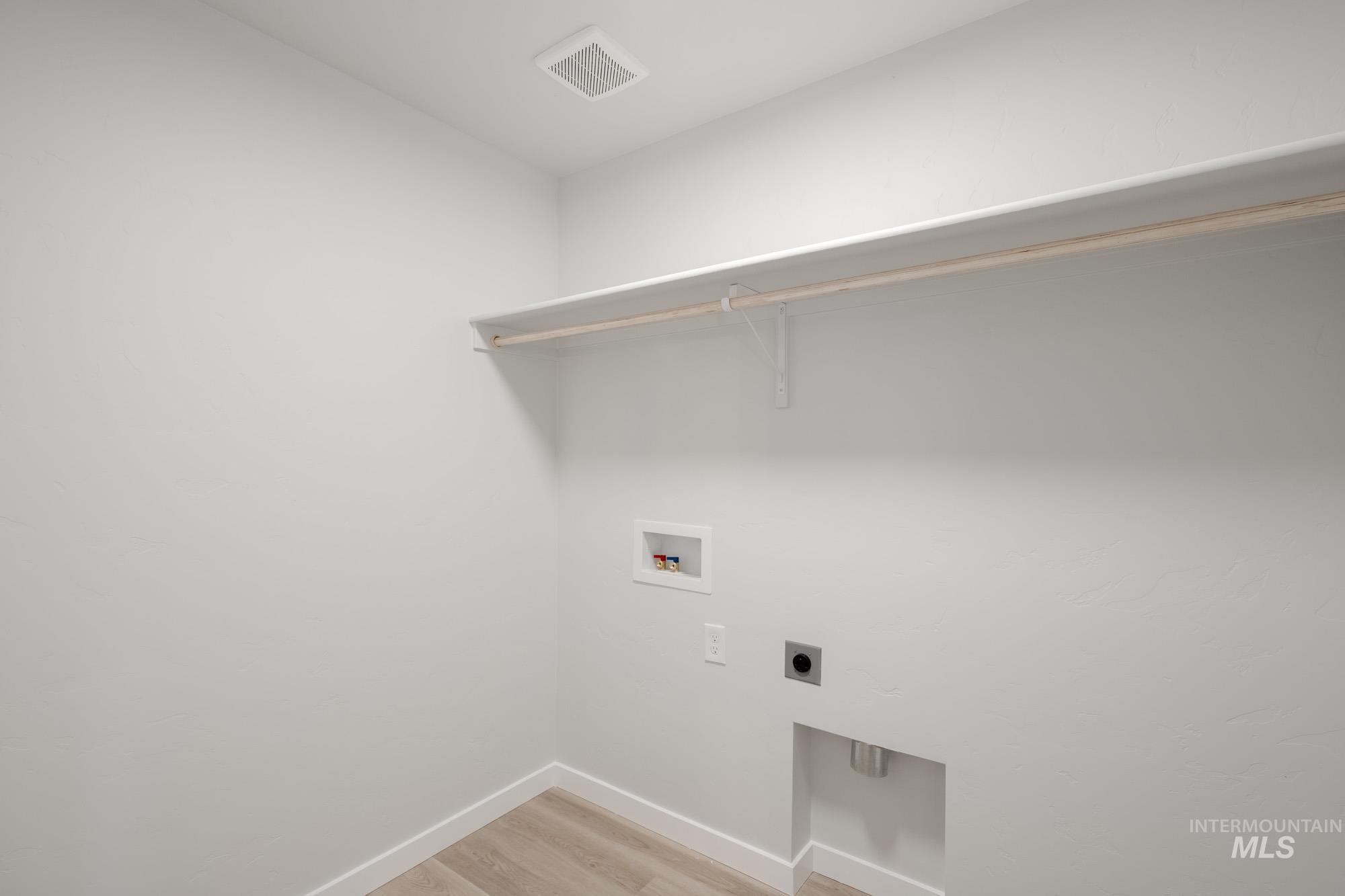 Laundry area featuring light wood-type flooring, hookup for a washing machine, and electric dryer hookup