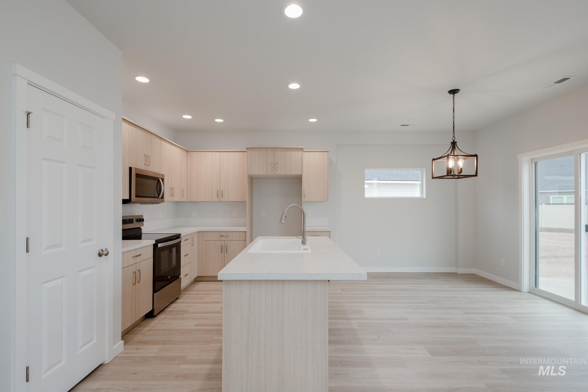 Kitchen with appliances with stainless steel finishes, light countertops, recessed lighting, light brown cabinets, and light wood-type flooring