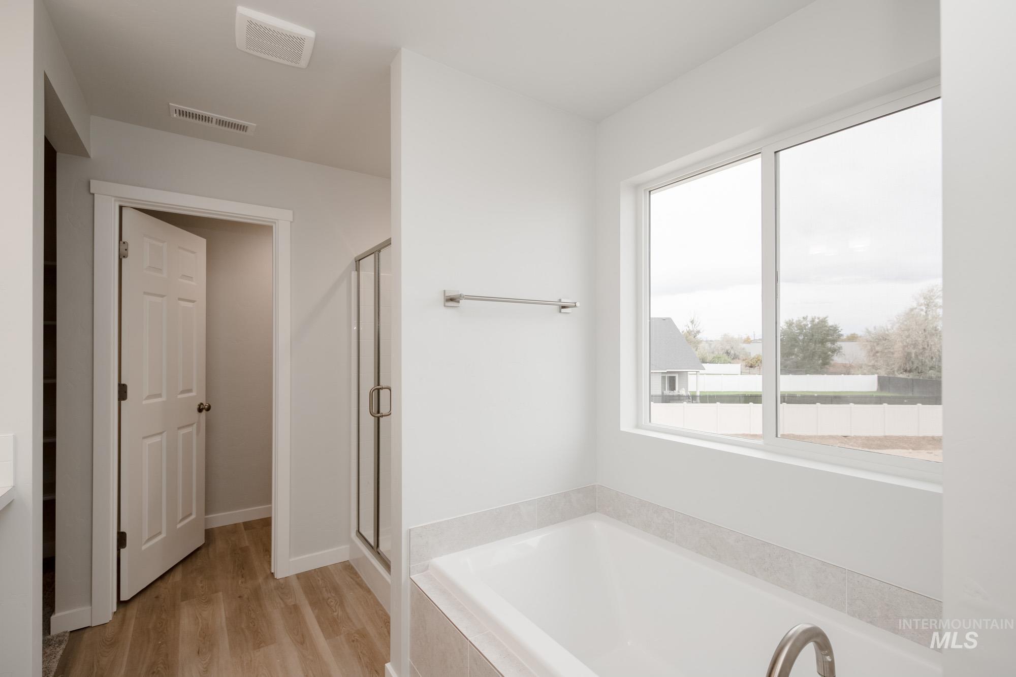 Full bath featuring a garden tub, a shower stall, light wood-style floors, and vanity