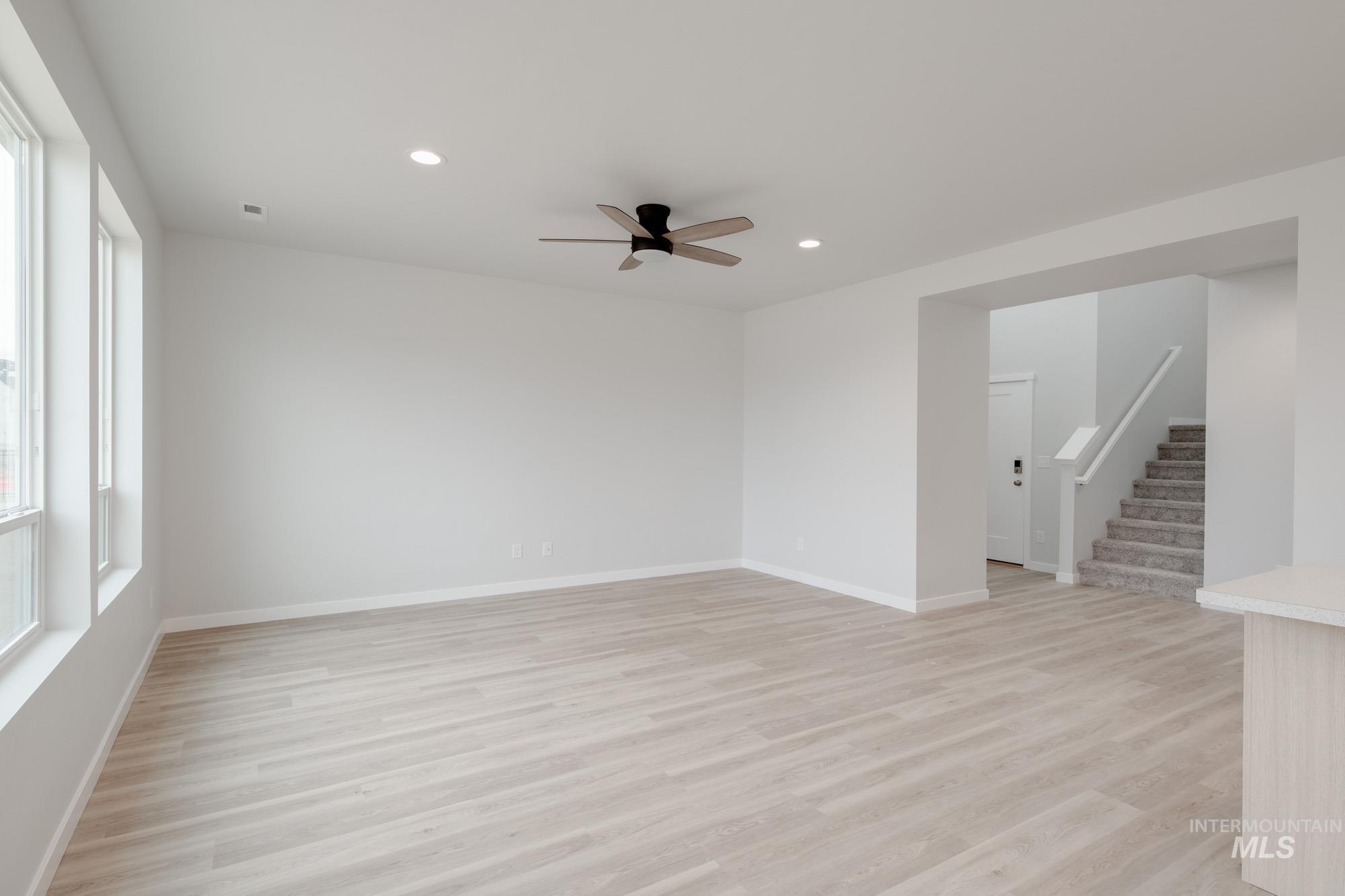Empty room with light wood-type flooring, stairs, ceiling fan, and recessed lighting