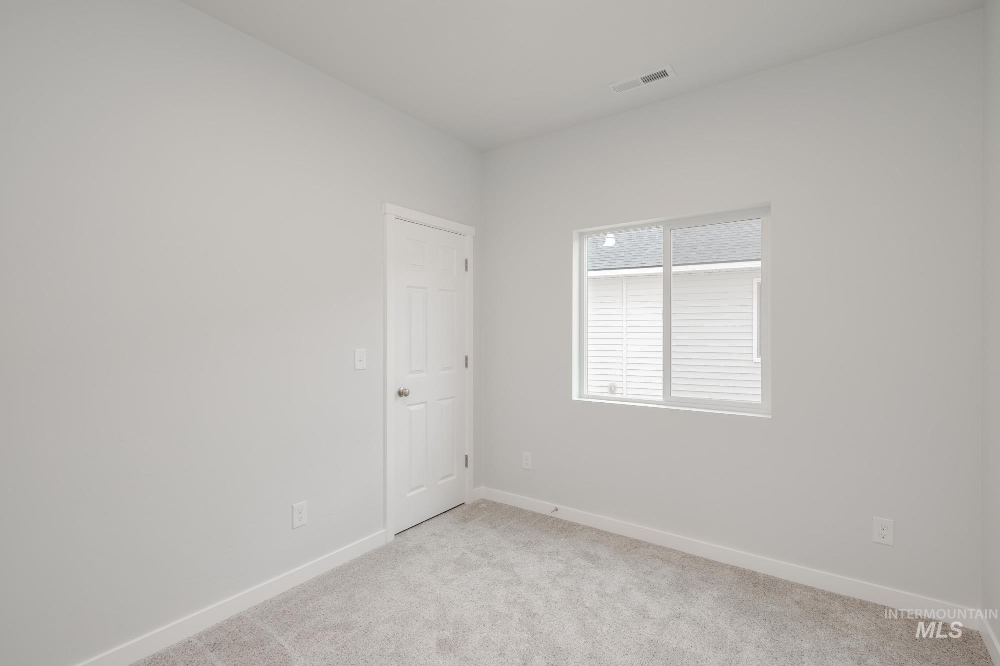 Unfurnished room featuring light carpet and baseboards