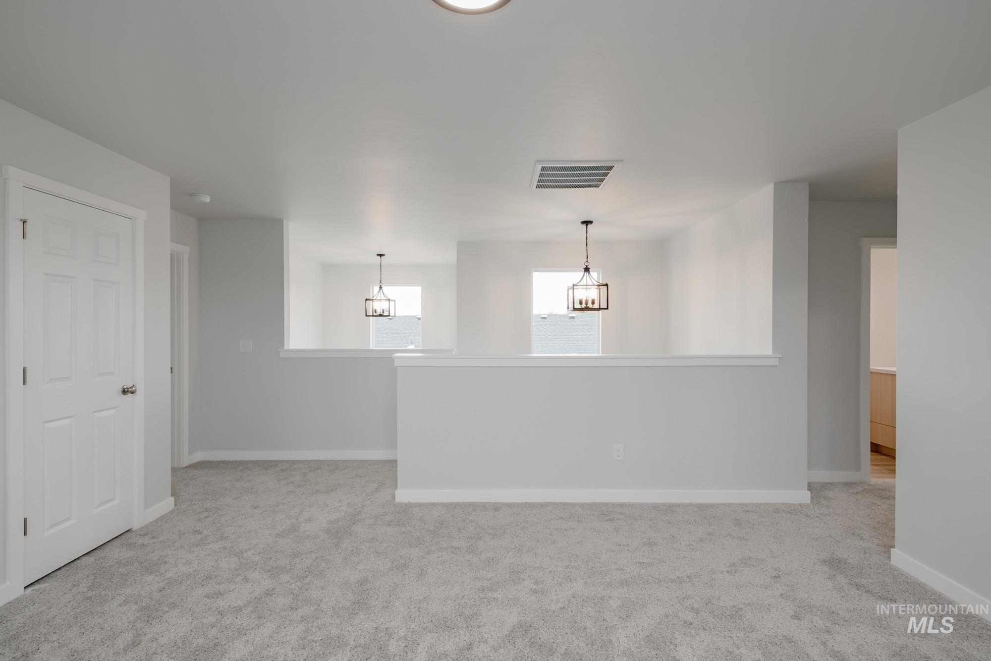 Spare room featuring light colored carpet and baseboards