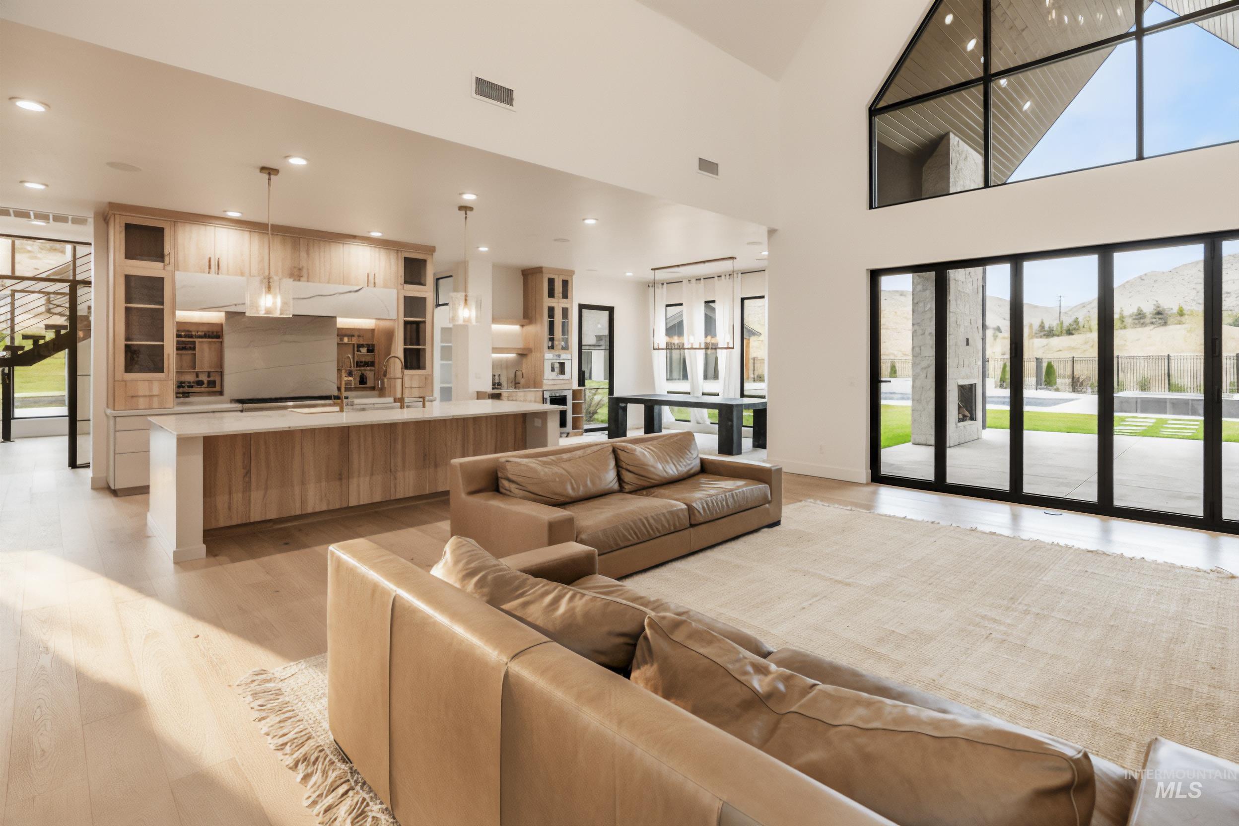 Living room featuring light wood-style floors, a towering ceiling, and recessed lighting