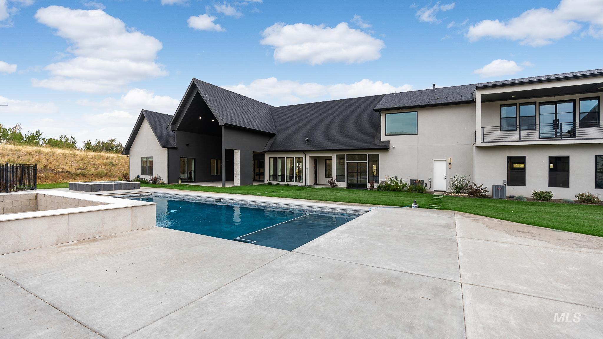 Swimming pool with an in-ground hot tub, a patio, and a yard