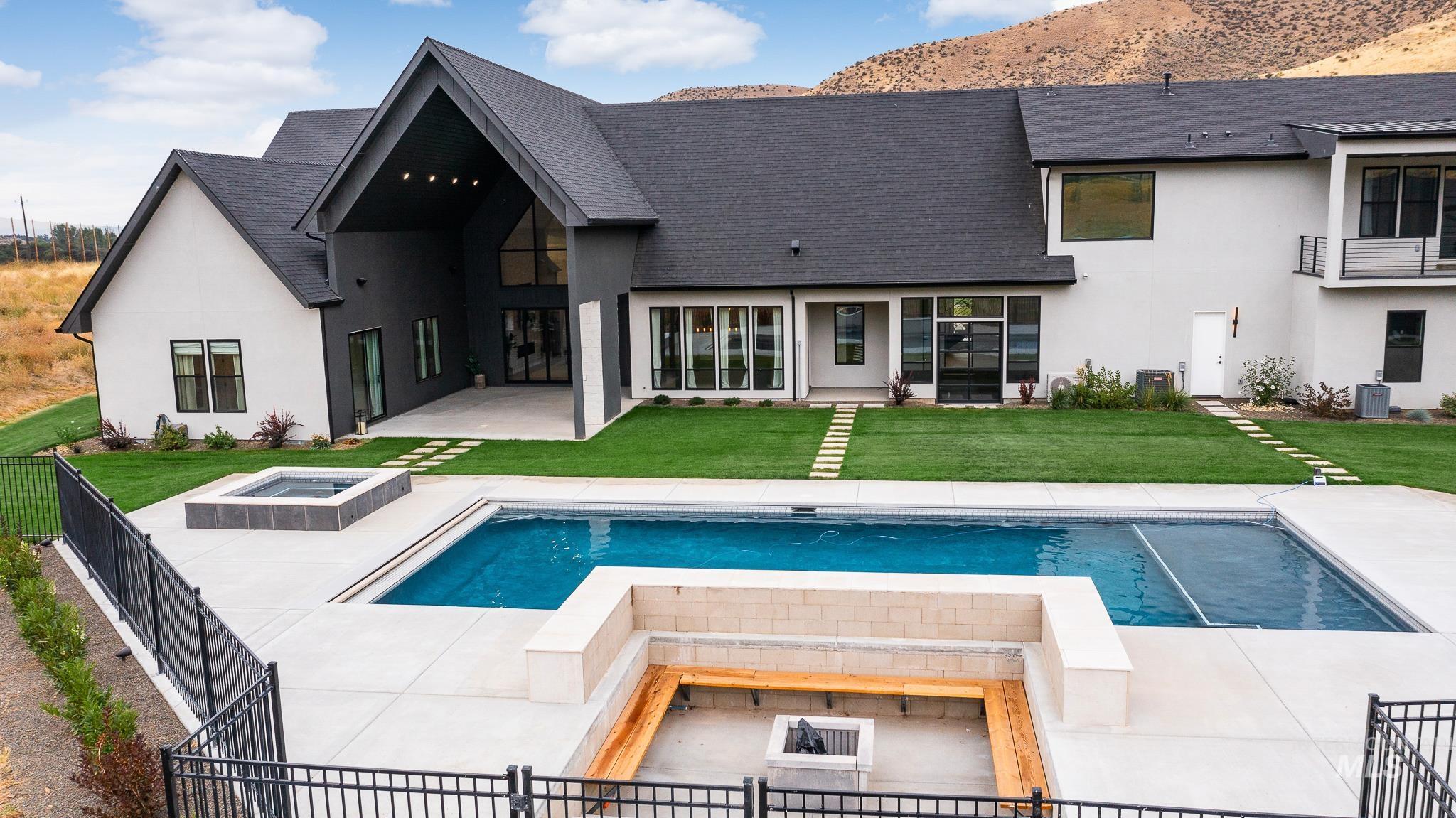 Back of house featuring a patio, a hot tub, stucco siding, and a shingled roof