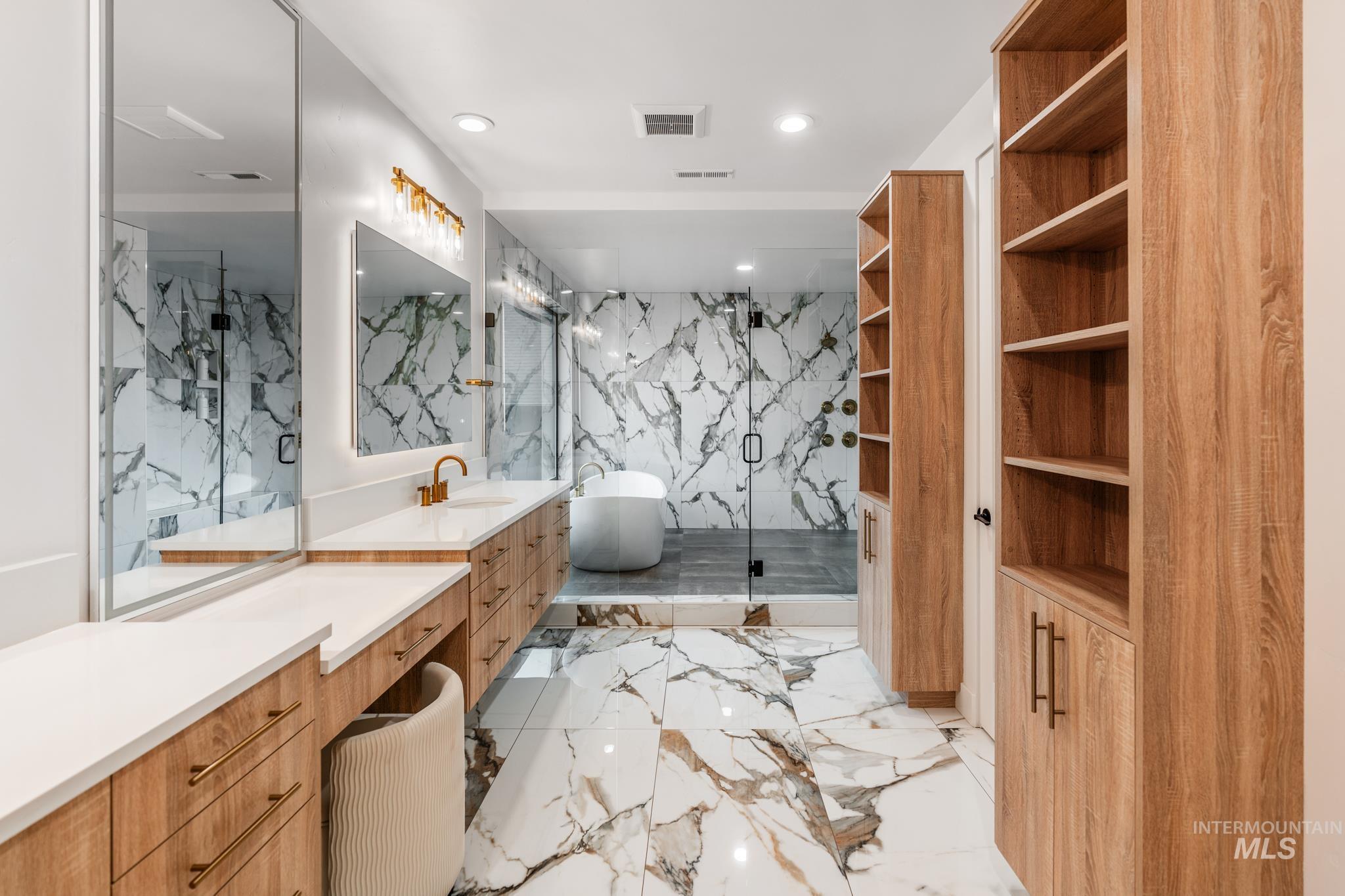 Bathroom featuring light marble finish flooring, stone wall, a marble finish shower, vanity, and a soaking tub