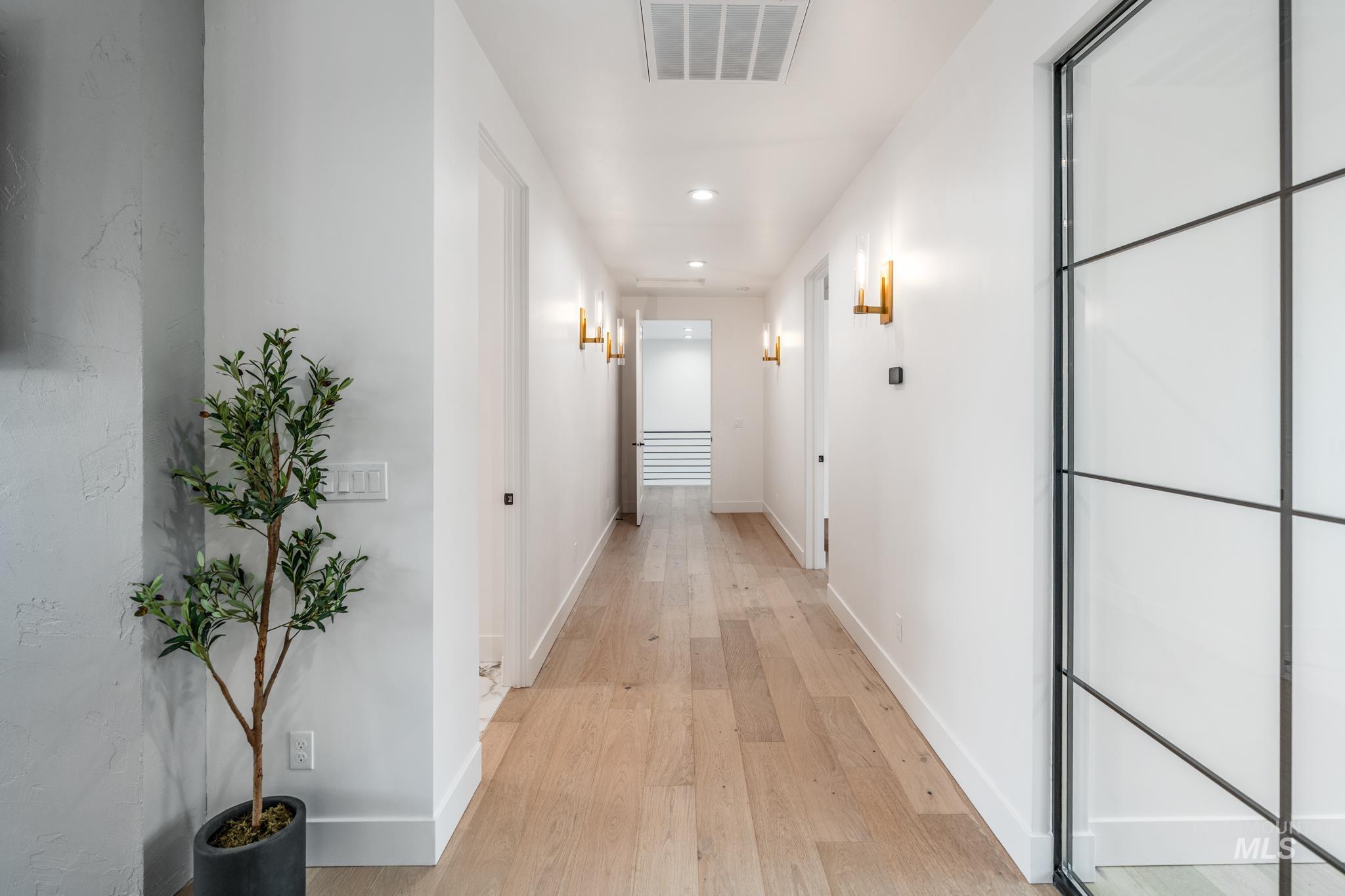 Hallway with light wood-type flooring and recessed lighting