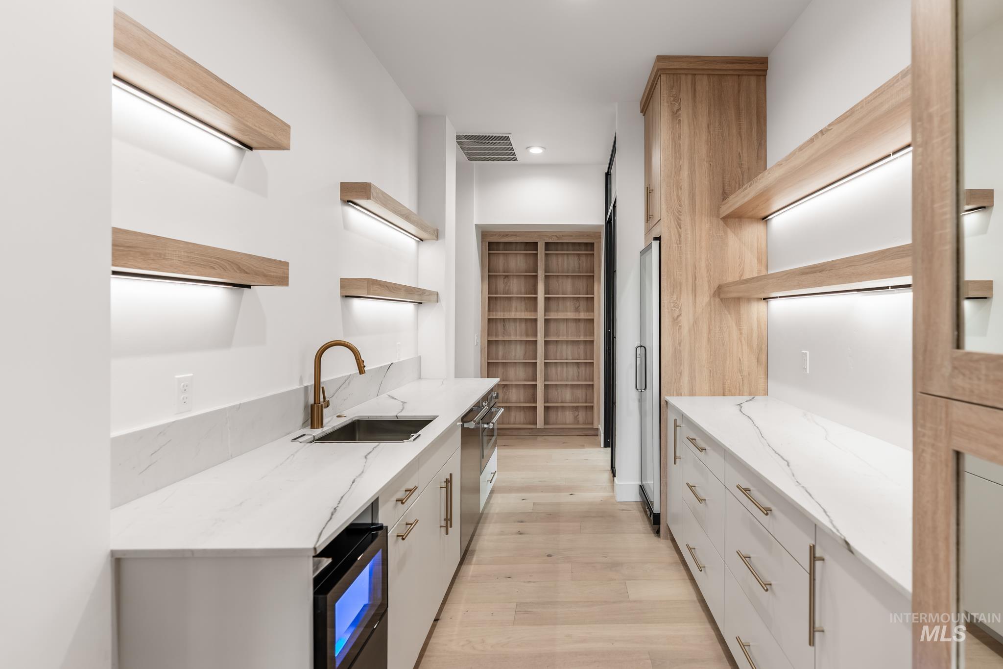 Kitchen featuring open shelves, light stone counters, light wood-style floors, and recessed lighting