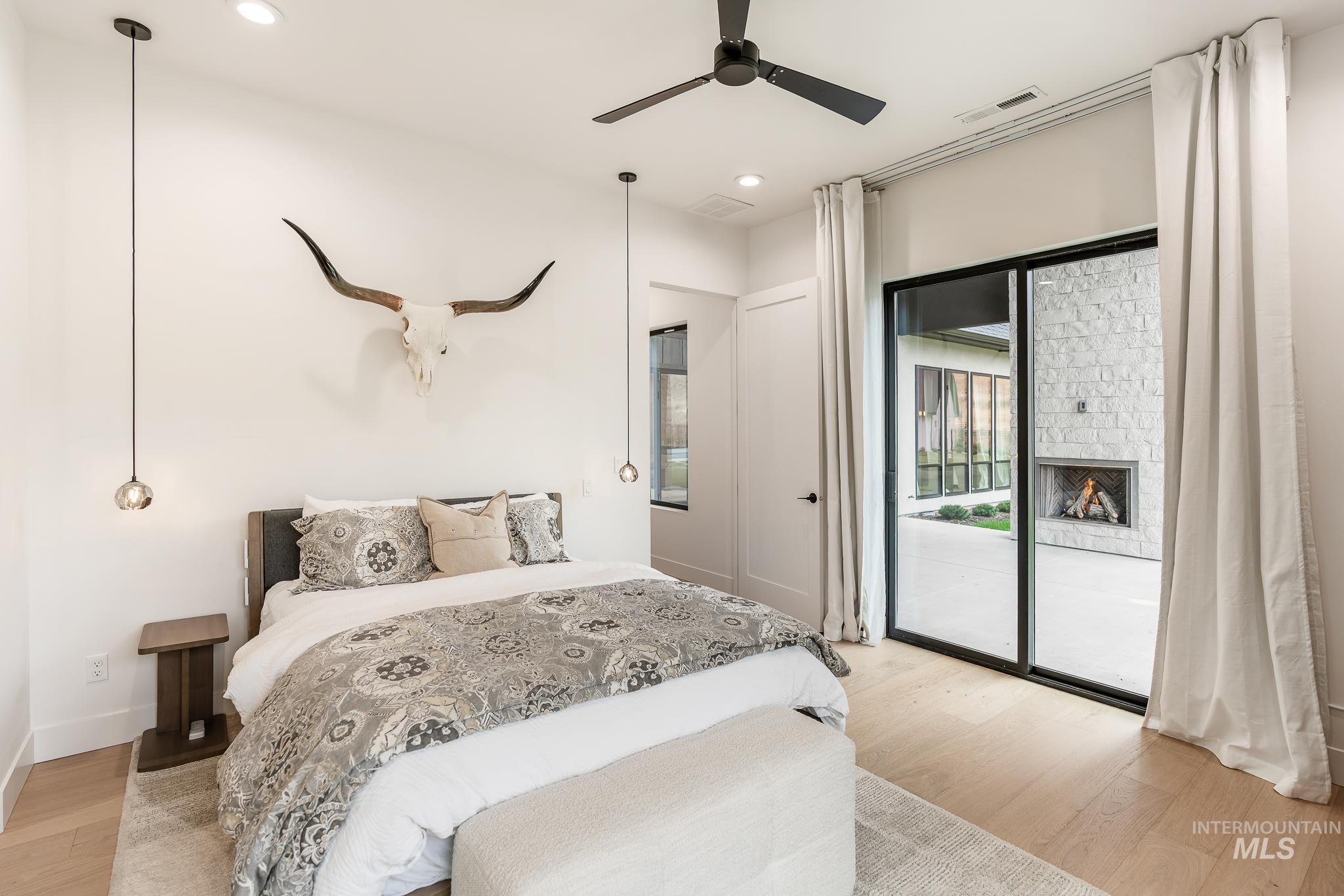 Bedroom with light wood-style floors, recessed lighting, ceiling fan, access to exterior, and a fireplace