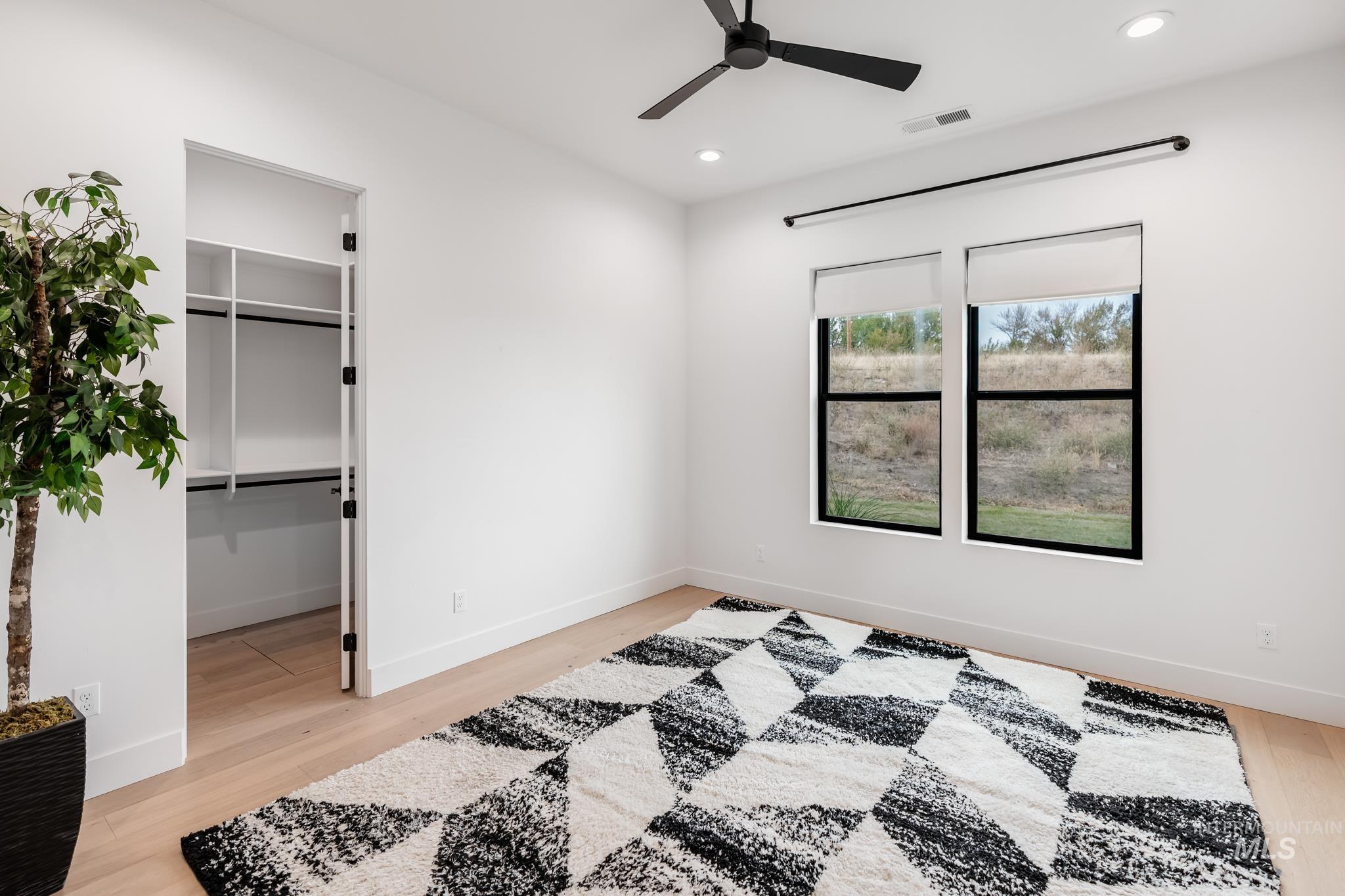 Bedroom featuring a spacious closet, light wood-style flooring, ceiling fan, and recessed lighting